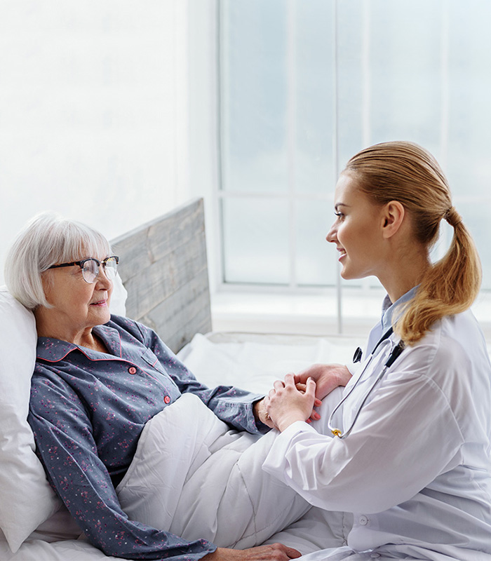 a caregiver with an elderly woman in bed