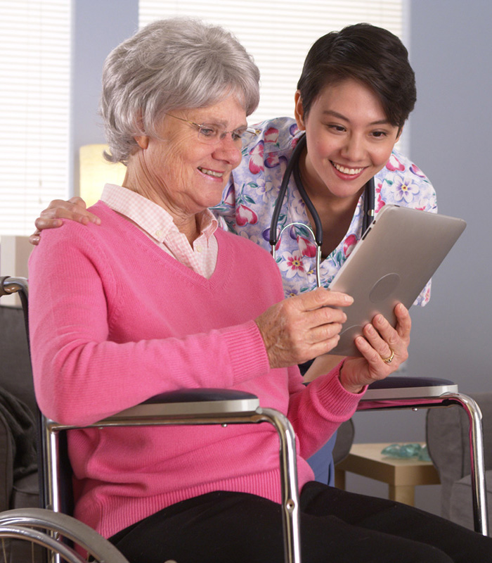 a caregiver with an elderly woman in a wheelchair in her home